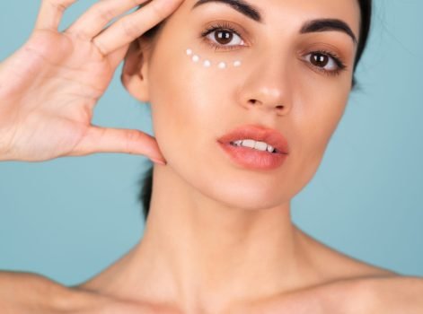 Close-up beauty portrait of a topless woman with perfect skin and natural make-up, with anti-aging cream dots to moisturize and firm the skin under the eyes